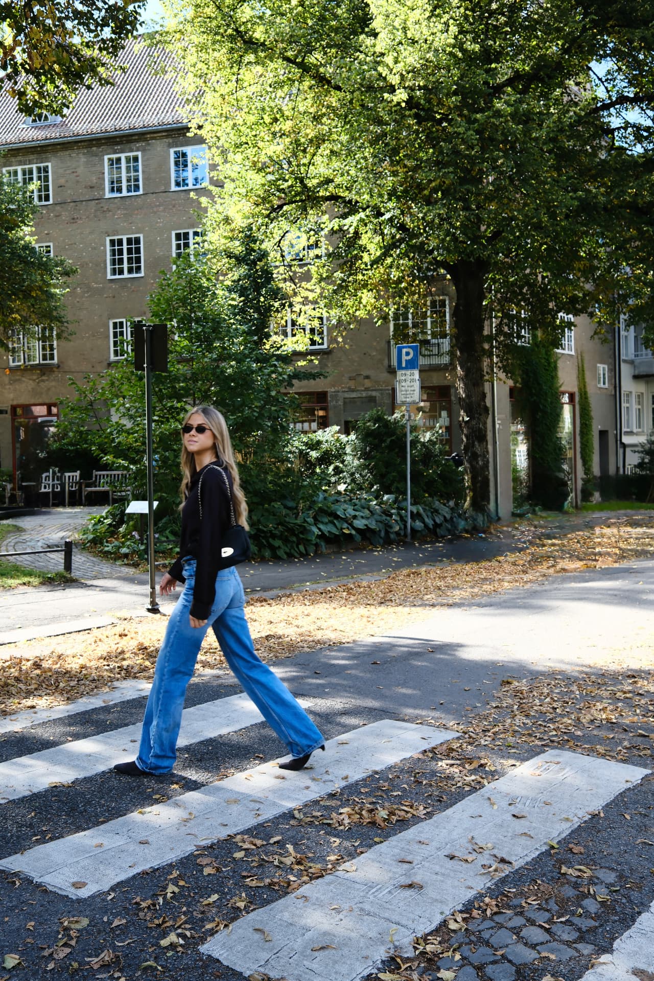 Kvinne i solbriller som går over et gangfelt i solfylt Oslo — KRE@IVE STUDIOS editorial