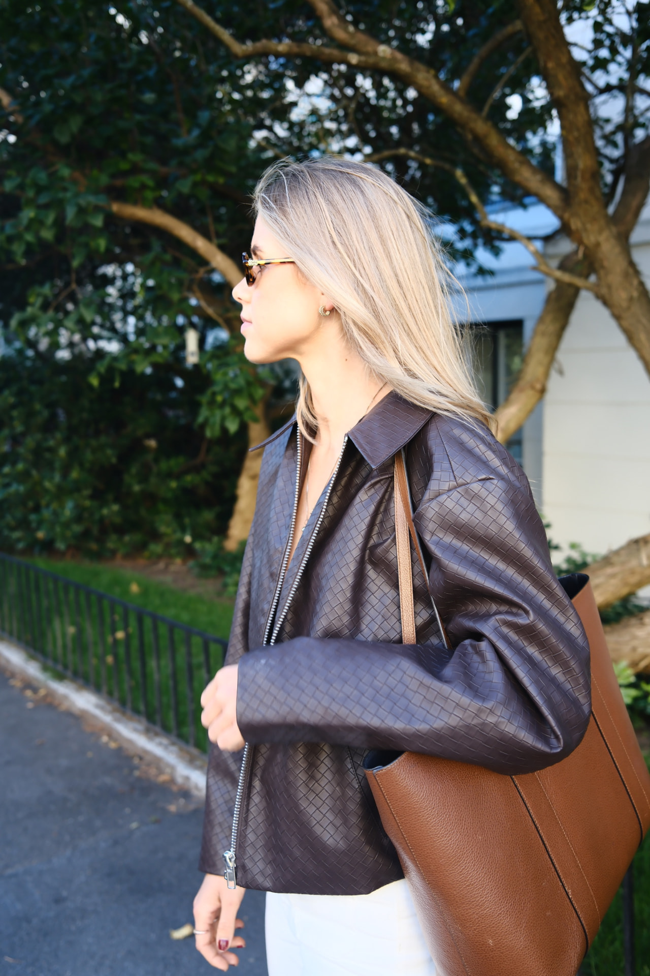 Kvinne i profil i mørkebrun læderjakke med tan bag i Oslo — KRE@IVE STUDIOS editorial